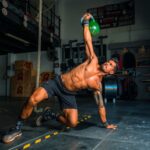 man in black shorts and black tank top doing push up