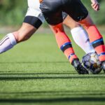 woman in black and white soccer jersey kicking soccer ball on green field during daytime