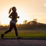 woman in black sports bra and black pants running on water during sunset