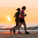 woman in black tank top and black shorts running on beach during sunset